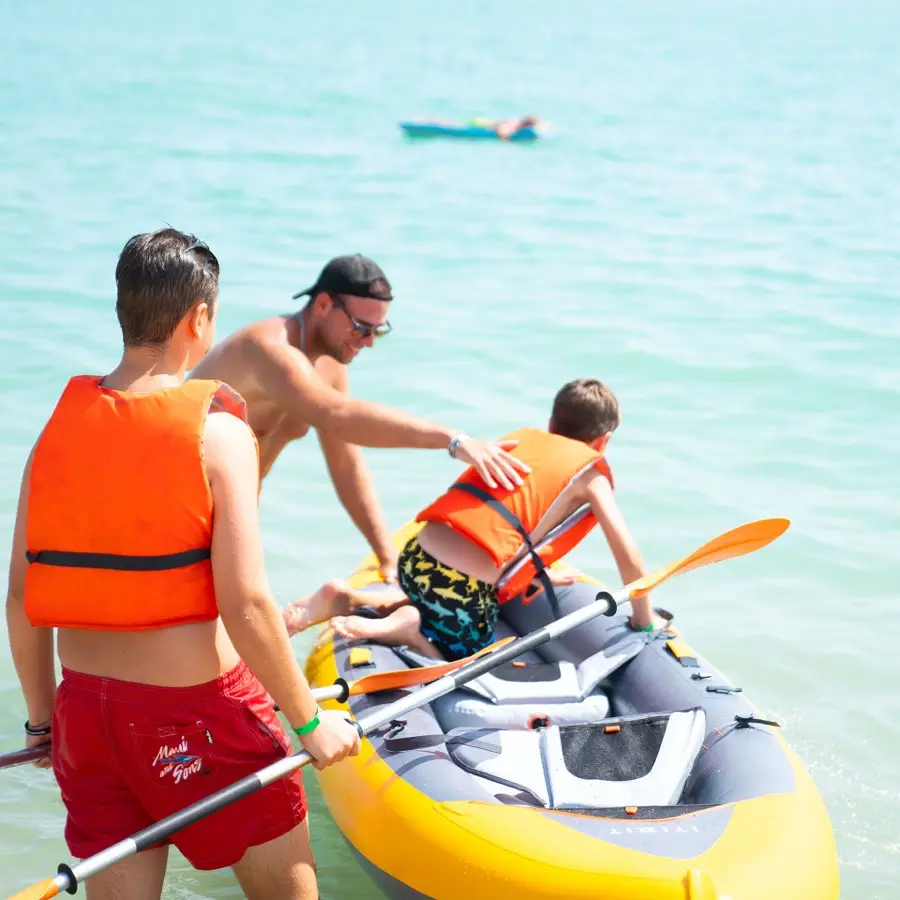 Istruttore aiuta un bambino a salire sul kayak